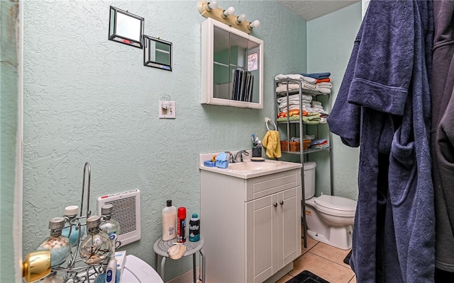 bathroom with tile patterned flooring, vanity, toilet, and walk in shower