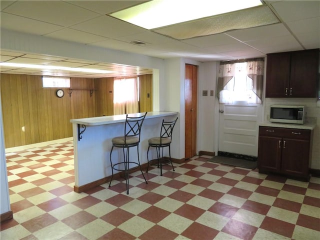 kitchen featuring wooden walls, a breakfast bar, and a wealth of natural light