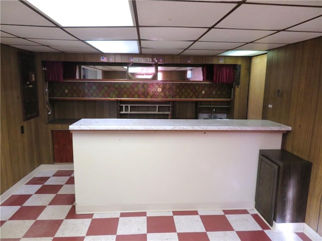 kitchen with a paneled ceiling and wooden walls