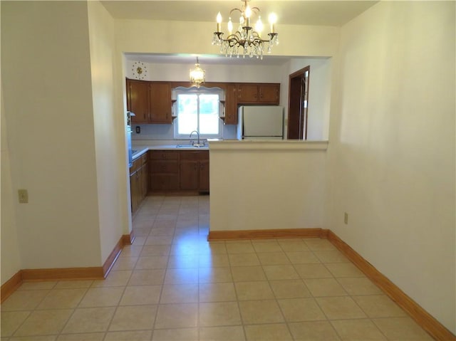 kitchen with sink, an inviting chandelier, white refrigerator, decorative light fixtures, and light tile patterned floors