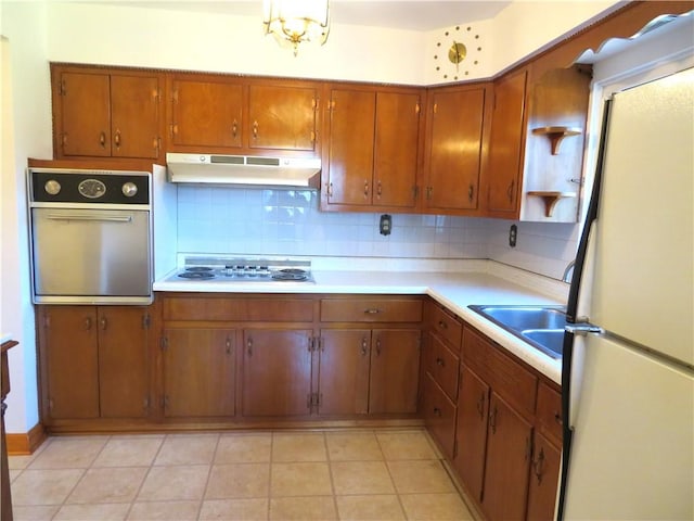 kitchen featuring sink, backsplash, a chandelier, white appliances, and light tile patterned floors