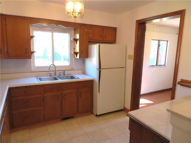 kitchen with pendant lighting, an inviting chandelier, sink, decorative backsplash, and white fridge