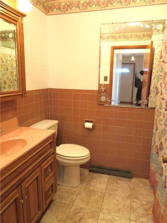 bathroom with tile patterned flooring, vanity, toilet, and tile walls