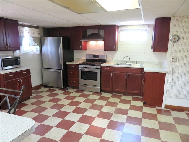 kitchen with a paneled ceiling, backsplash, sink, wall chimney exhaust hood, and appliances with stainless steel finishes