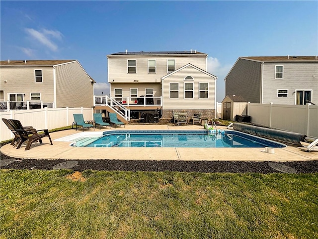 back of house featuring a patio, a covered pool, and a lawn