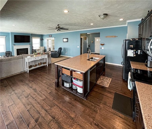 kitchen with ceiling fan, sink, stainless steel appliances, dark wood-type flooring, and a kitchen island with sink