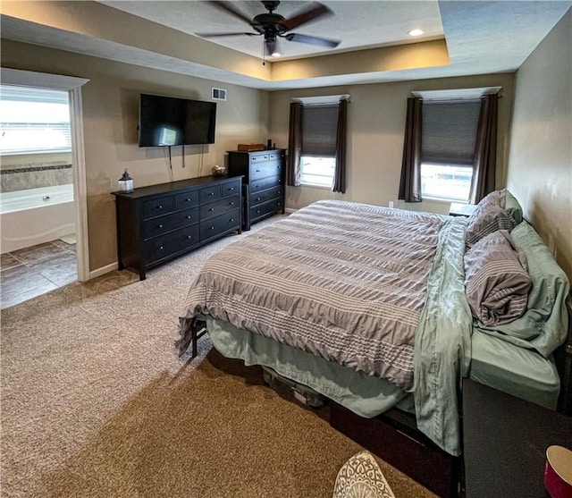 carpeted bedroom featuring ceiling fan and a raised ceiling