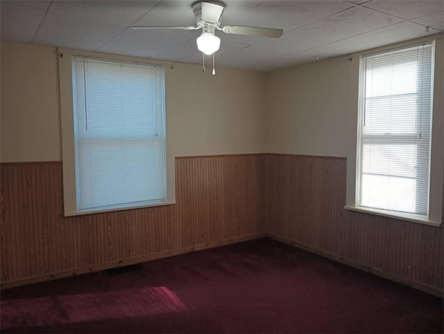 spare room with carpet flooring, ceiling fan, and wood walls