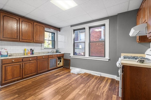 kitchen featuring dark hardwood / wood-style flooring, a paneled ceiling, white gas stove, and exhaust hood