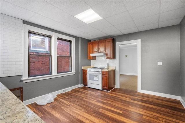 kitchen featuring white range with gas stovetop, dark hardwood / wood-style flooring, a drop ceiling, and backsplash