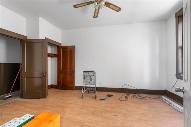 exercise room with ceiling fan and light wood-type flooring