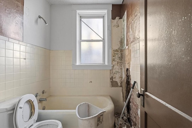 bathroom with a bathtub, tile walls, and toilet