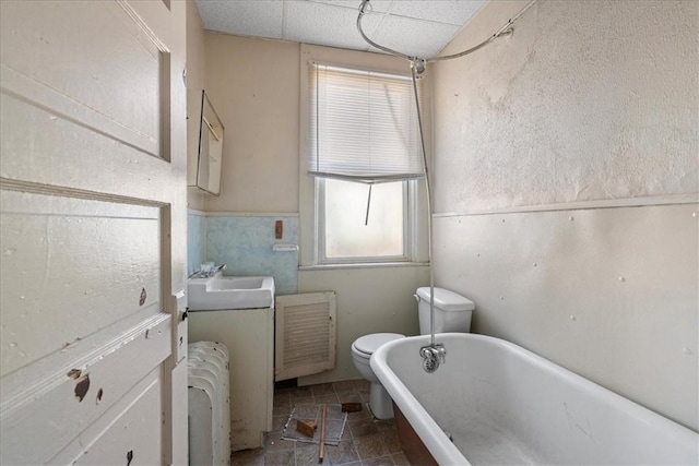 bathroom with radiator heating unit, a tub to relax in, a healthy amount of sunlight, and sink