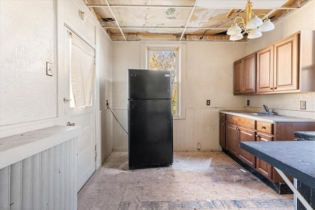 kitchen with black refrigerator, a chandelier, and sink