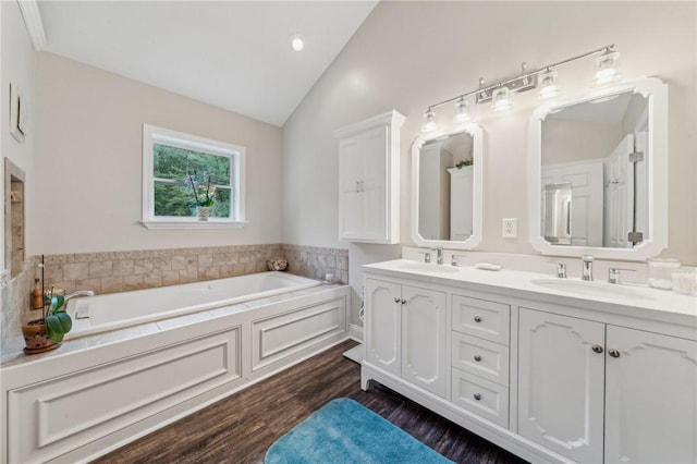 bathroom featuring lofted ceiling, a bathtub, wood-type flooring, and vanity