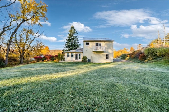 back of property featuring a lawn and a balcony