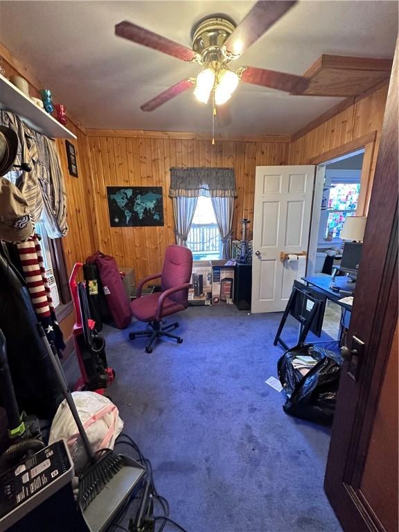 misc room featuring carpet, ceiling fan, and wood walls