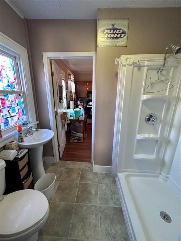 bathroom featuring a shower, tile patterned floors, toilet, and ornamental molding