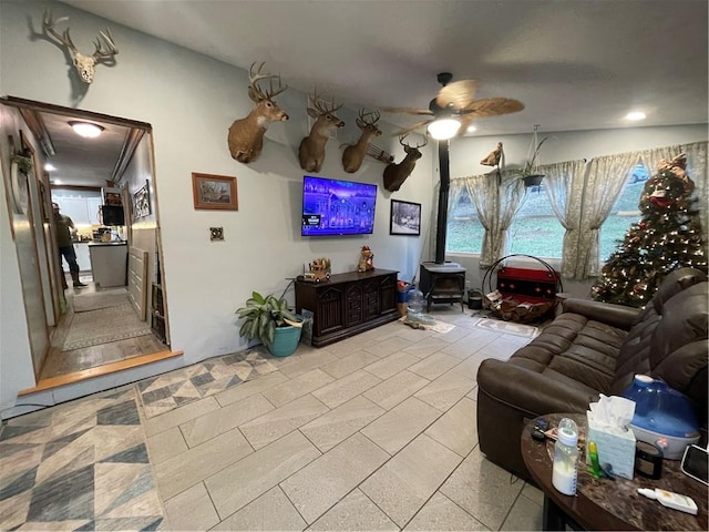 living room featuring ceiling fan and a wood stove