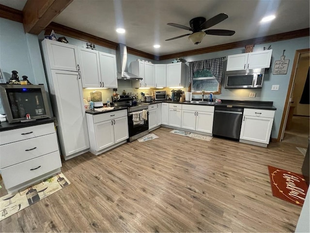 kitchen with white cabinets, sink, wall chimney exhaust hood, light wood-type flooring, and appliances with stainless steel finishes