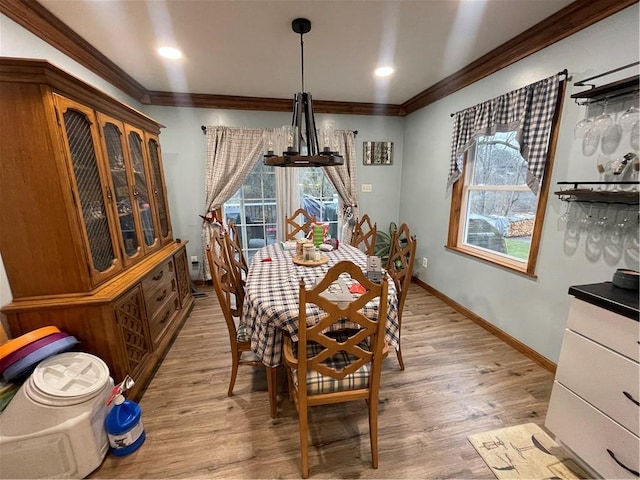 dining area with a chandelier, light hardwood / wood-style flooring, a healthy amount of sunlight, and ornamental molding