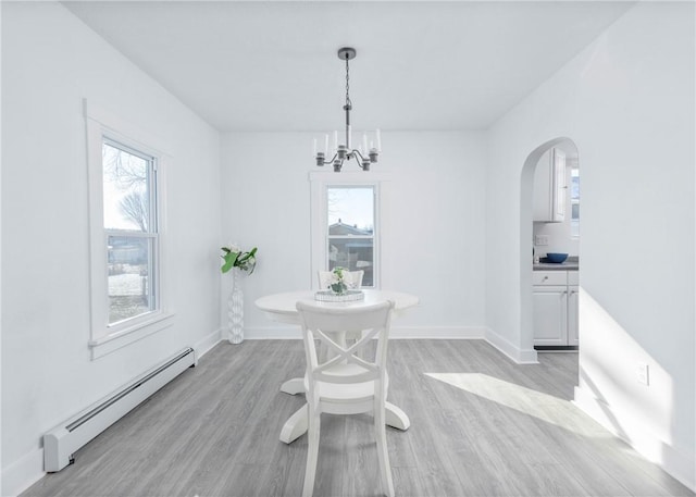 dining room with light wood-type flooring, plenty of natural light, a baseboard heating unit, and a notable chandelier