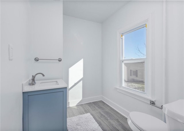 bathroom with a wealth of natural light, toilet, vanity, and hardwood / wood-style flooring