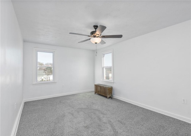 carpeted spare room featuring radiator, ceiling fan, and a textured ceiling