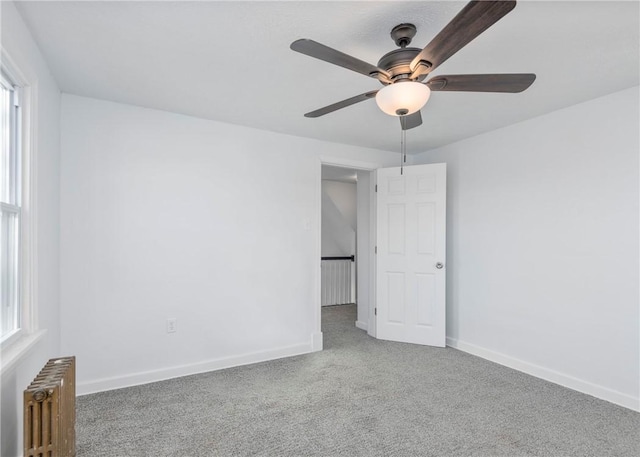 carpeted spare room with radiator heating unit and ceiling fan