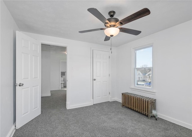 unfurnished bedroom featuring radiator heating unit, dark carpet, and ceiling fan