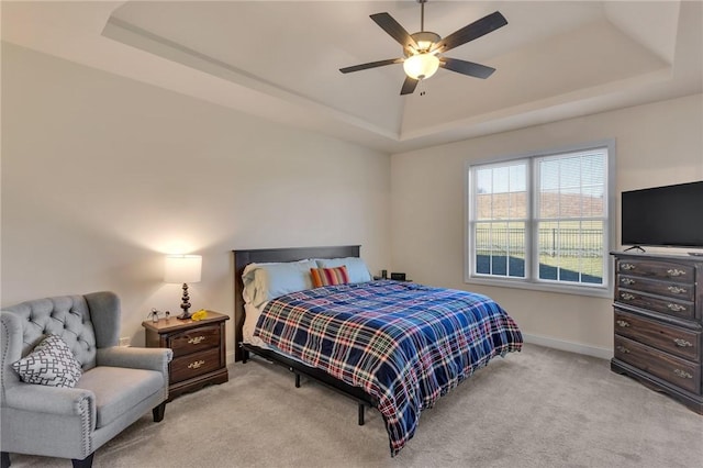 carpeted bedroom with ceiling fan and a tray ceiling