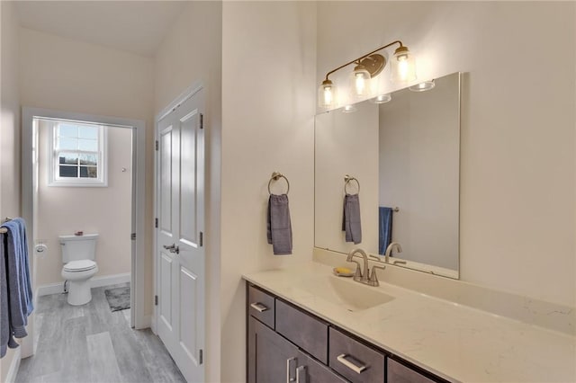 bathroom featuring vanity, wood-type flooring, and toilet