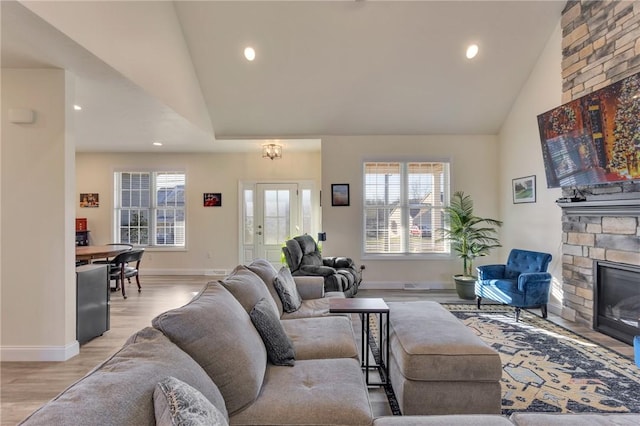 living room with a fireplace, high vaulted ceiling, and light hardwood / wood-style flooring