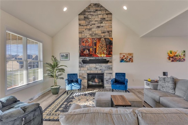 living room with a stone fireplace, high vaulted ceiling, and hardwood / wood-style flooring