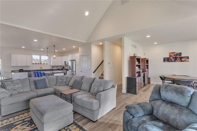 living room with light hardwood / wood-style floors and high vaulted ceiling