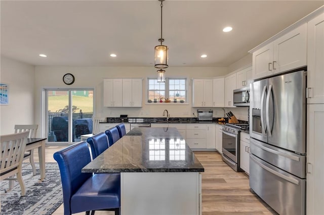 kitchen with a center island, white cabinets, sink, light hardwood / wood-style flooring, and stainless steel appliances