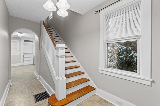 staircase featuring tile patterned floors, a chandelier, and a textured ceiling