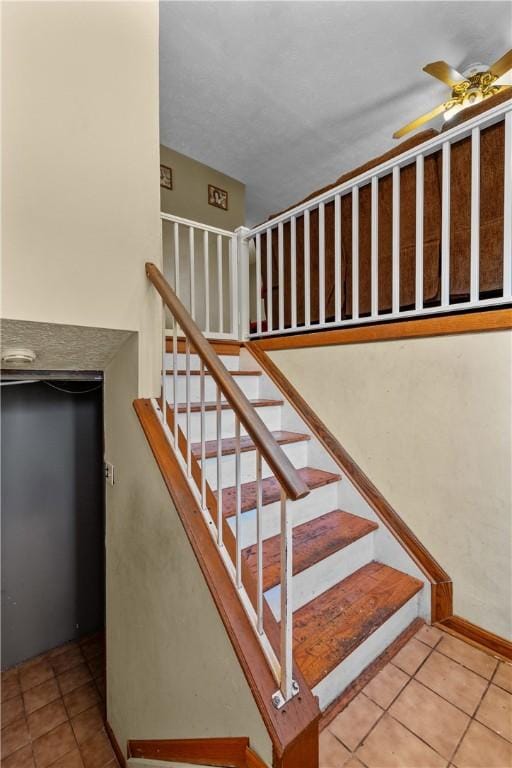 stairway with ceiling fan and tile patterned floors