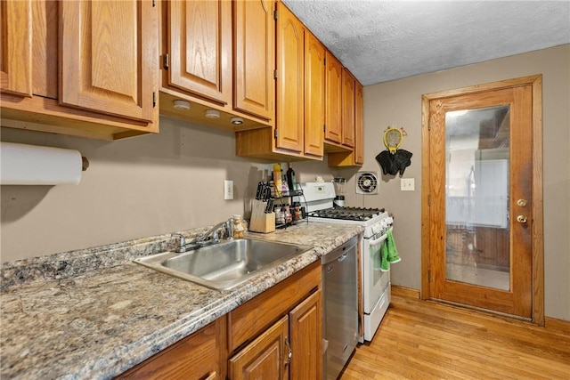 kitchen featuring sink, white range with gas stovetop, stainless steel dishwasher, light hardwood / wood-style floors, and a textured ceiling