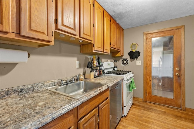 kitchen featuring light wood-type flooring, a textured ceiling, white range with gas stovetop, stainless steel dishwasher, and a sink