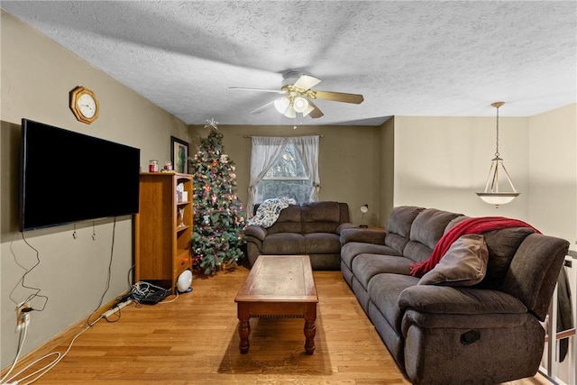 living room with ceiling fan, a textured ceiling, and light hardwood / wood-style flooring