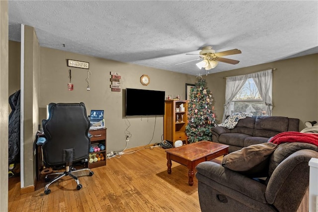 living room with a textured ceiling, light hardwood / wood-style flooring, and ceiling fan