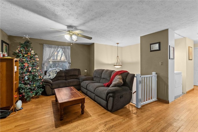 living room featuring ceiling fan, light hardwood / wood-style floors, and a textured ceiling