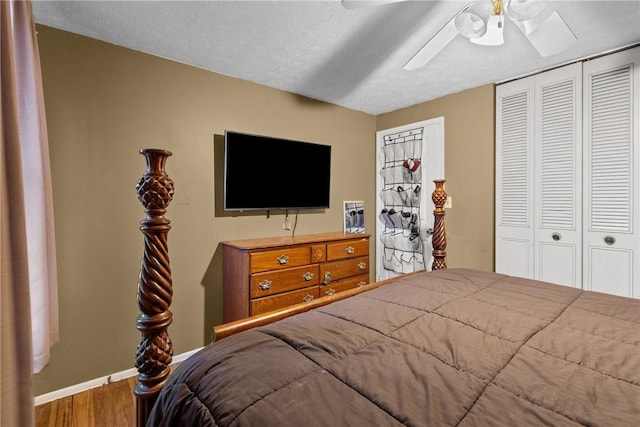 bedroom featuring a closet, baseboards, a textured ceiling, a ceiling fan, and wood finished floors