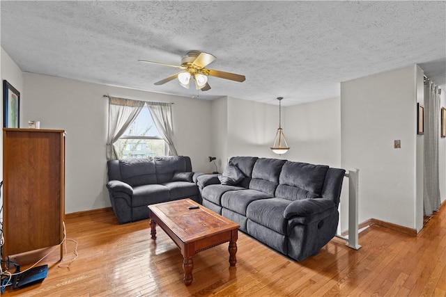 living area with light wood-style flooring, a ceiling fan, baseboards, and a textured ceiling