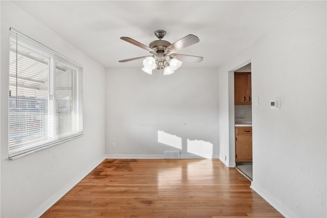 empty room with a ceiling fan, light wood-type flooring, and baseboards