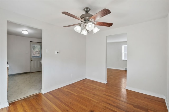 spare room with baseboards, ceiling fan, and light wood-style floors