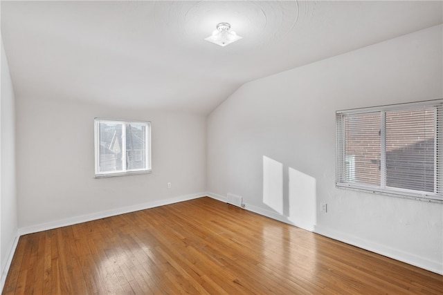 additional living space featuring visible vents, baseboards, vaulted ceiling, and hardwood / wood-style floors