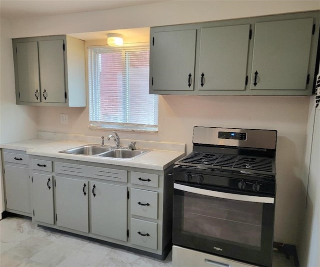 kitchen featuring marble finish floor, light countertops, a sink, and stainless steel gas range oven