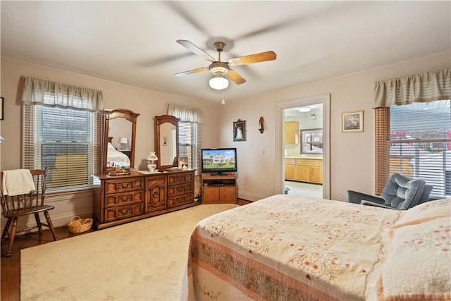 bedroom featuring hardwood / wood-style floors, ensuite bathroom, multiple windows, and ceiling fan